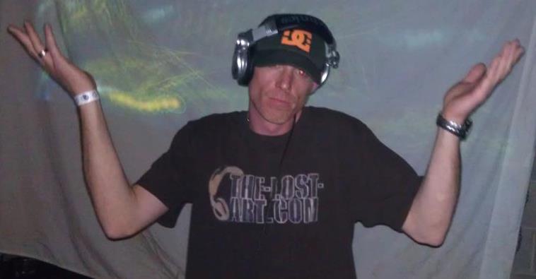 DJ Natural Nate® in The-Lost-Art™ shirt with arms raised on stage